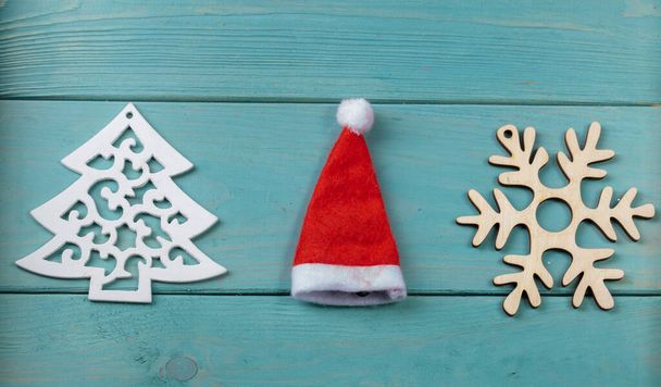 Sur la surface en bois turquoise se trouve un flocon de neige et un chapeau de Noël. - Photo, image