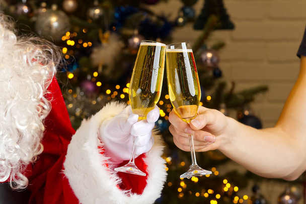 サンタはシャンパンのグラスを舐める。シャンパングラスをクリックし、一緒にクリスマスや新年を祝う - 写真・画像