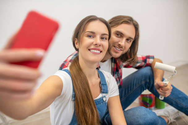 Young happy couple sitting on the floor and making selfie - Foto, immagini