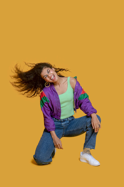 Pretty dark-haired young girl in bright jacket making poses and looking happy - Foto, Imagen