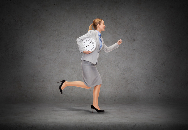 Smiling young businesswoman with clock running - Photo, Image