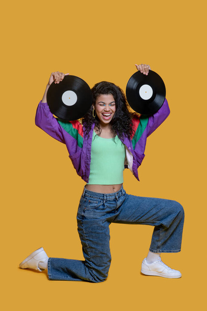 Cute dark-haired young girl holding records and having fun - 写真・画像