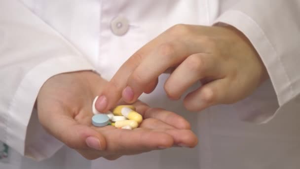 手に複数の色の錠剤。接近中だ。鎮痛剤だ。抗うつ薬だ。健康的な生活のための薬。白いコートの医者は多くの薬の処方箋を書いた - 映像、動画
