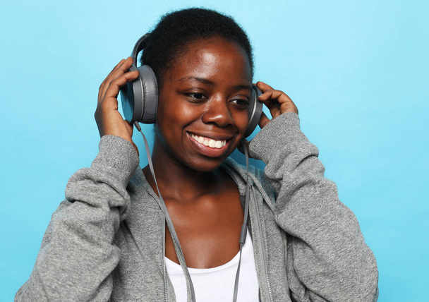 Bella donna africana che ascolta musica su sfondo blu - Foto, immagini