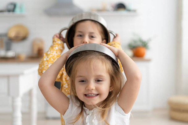Cute little kids wearing bowl as helmet and playing at home. - Foto, Imagen