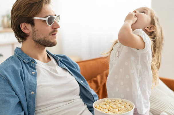 Happy family watching TV at home and eating popcorn. - Photo, Image
