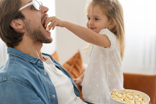 Happy family watching TV at home and eating popcorn. - Φωτογραφία, εικόνα