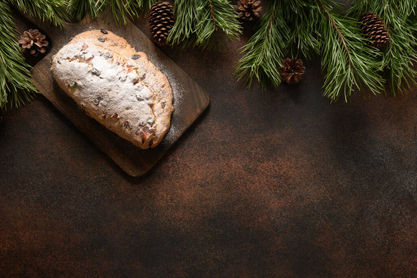 Christmas traditional stollen on brown background with copy space. Xmas greeting card. View from above. Flat lay style. - Photo, Image