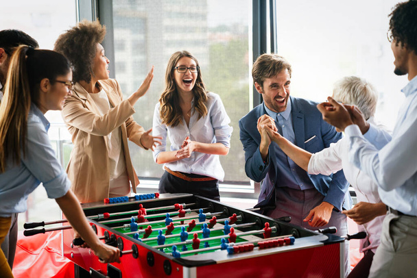 Coworkers playing table football and relaxing on break from work - Фото, зображення