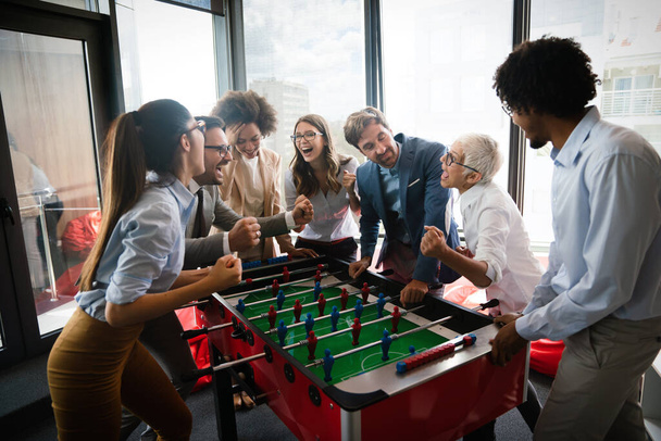 Coworkers playing table football and relaxing on break from work - 写真・画像