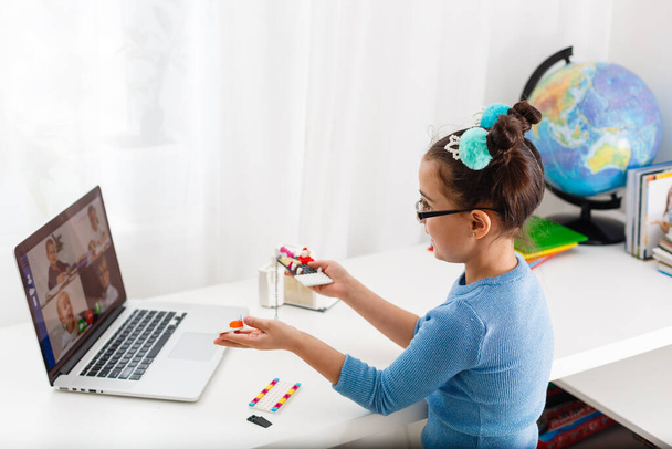 Pieni tiedemies työskentelee uuden projektin parissa, pieni tyttö opiskelee robotiikkaa kannettavalla tietokoneella verkossa - Valokuva, kuva