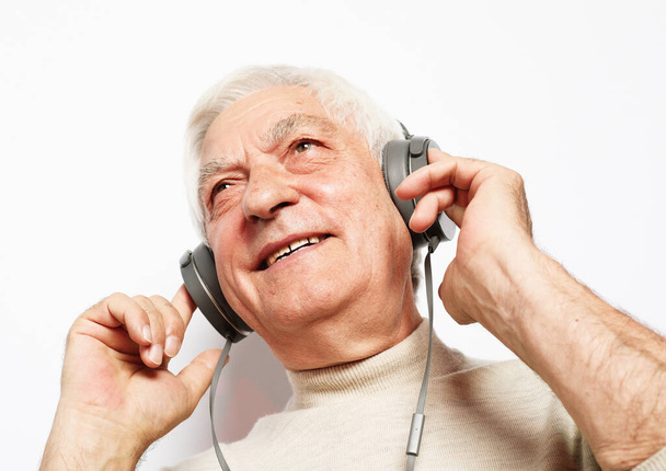 lifestyle, tehnology and people concept: Old man listening to music with headphones over white background - Фото, зображення