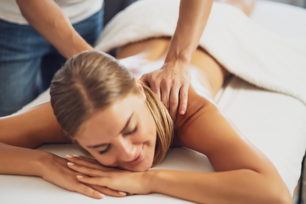 Masajista profesional haciendo masaje terapéutico. Mujer disfrutando de masajes en su casa. Mujer joven recibiendo masaje corporal relajante. - Foto, Imagen
