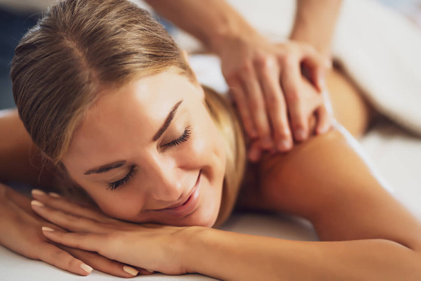 massagista profissional fazendo massagem terapêutica. Mulher desfrutando de massagem em sua casa. Jovem mulher recebendo relaxante massagem corporal. - Foto, Imagem