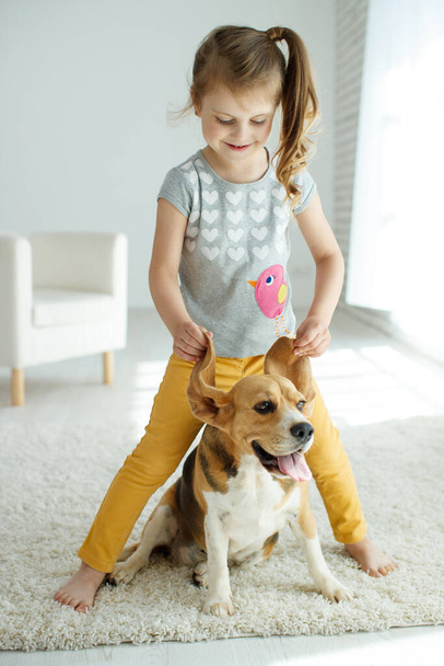 Little girl with a dog at home. - Фото, зображення