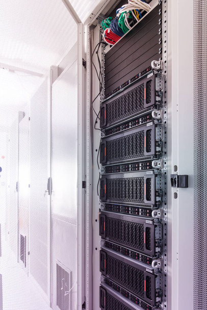Una fila de bastidores con hardware de almacenamiento de datos dentro de la sala de servidores - Foto, Imagen