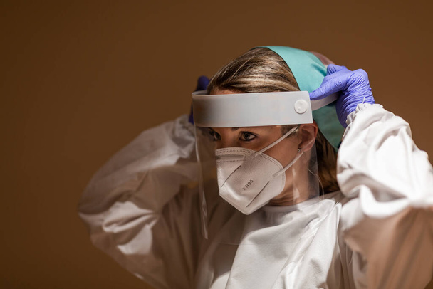 Медичний працівник у коронавірусі носить щит для обличчя та захисну маску
 - Фото, зображення