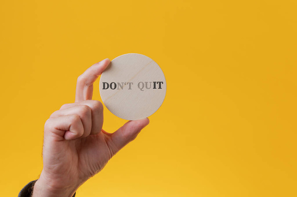 Dont quit sign spelled on wooden cut circle with a few letters vanishing to read a Do it sign. - Foto, immagini