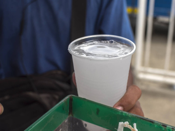 Sprzedawca uliczny trzyma plastikową filiżankę zimnego soku Buko. Znany również jako sok kokosowy, jest popularnym napojem na Filipinach. - Zdjęcie, obraz