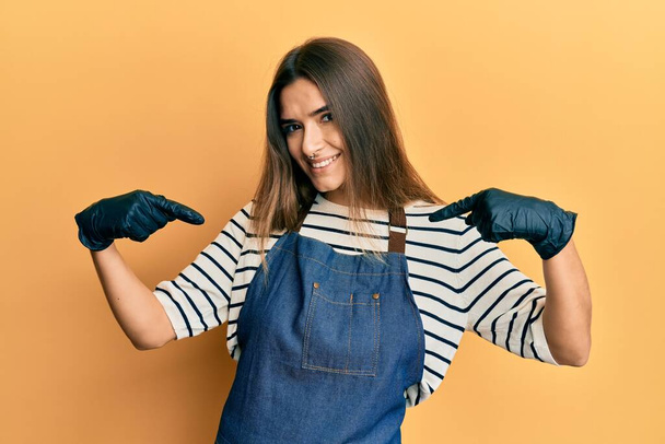Young hispanic woman wearing barber apron looking confident with smile on face, pointing oneself with fingers proud and happy.  - Фото, зображення