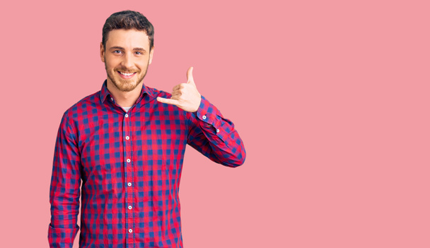 Handsome young man with bear wearing casual shirt smiling doing phone gesture with hand and fingers like talking on the telephone. communicating concepts.  - Photo, Image