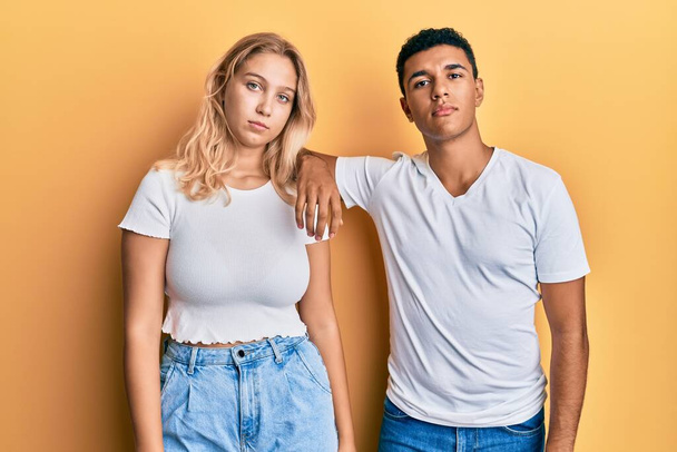 Young interracial couple wearing casual white tshirt relaxed with serious expression on face. simple and natural looking at the camera.  - Valokuva, kuva