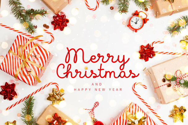 Boldog karácsonyi üdvözlőlapot ajándékdobozok, arany szalagok, fény, fenyő ág, cukornád és boldog karácsonyi szöveget. Újévi ünnepi háttér. Lapos fekvésű, felülnézet - Fotó, kép
