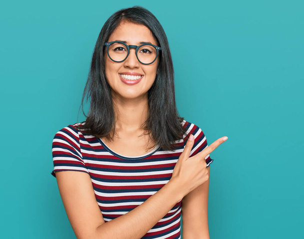 Beautiful asian young woman wearing casual clothes and glasses cheerful with a smile of face pointing with hand and finger up to the side with happy and natural expression on face  - Φωτογραφία, εικόνα