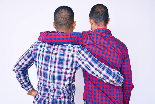 Νέοι γκέι δύο άντρες που φοράνε καθημερινά ρούχα και αγκαλιάζονται χαρούμενοι και θετικοί από την ανάποδη. αυτοαγάπη και αυτοφροντίδα  - Φωτογραφία, εικόνα