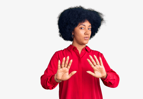 Młoda Afroamerykanka ubrana w luźne ubrania odsuwa dłonie, pokazując odmowę i zaprzeczenie ze strasznym i obrzydliwym wyrazem twarzy. zatrzymać i zabronione.  - Zdjęcie, obraz