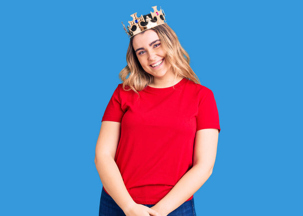 Jeune femme caucasienne portant la couronne de princesse regardant positif et heureux debout et souriant avec un sourire confiant montrant des dents  - Photo, image