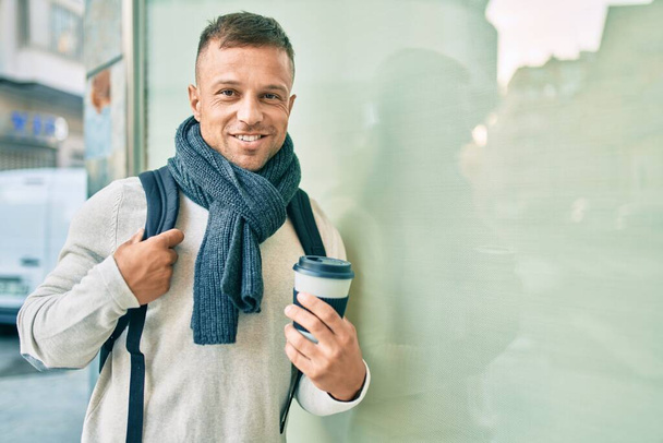 Giovane studente caucasico uomo sorridente felice bere portare via il caffè in città. - Foto, immagini