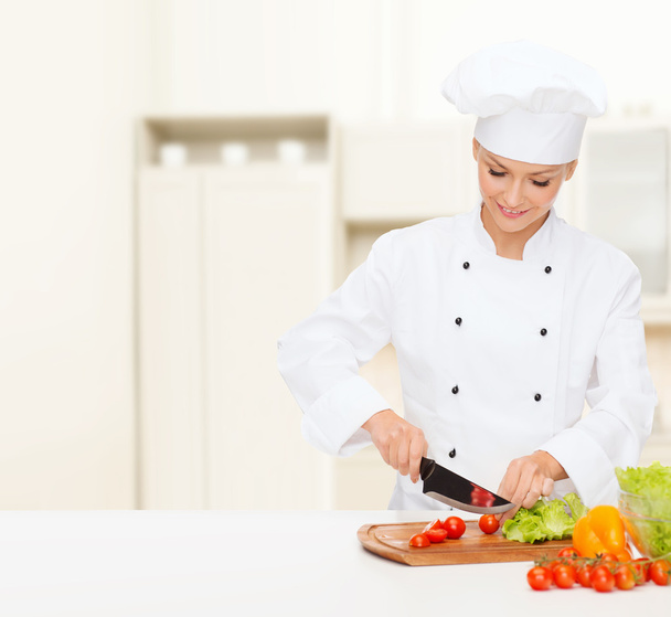 Smiling female chef chopping vagetables - Zdjęcie, obraz