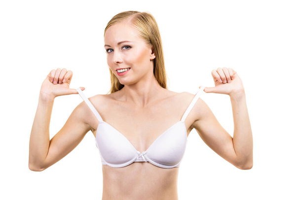 Smiling woman holding bra strap. Properly bra fitting. Female breast in white lingerie. Bosom and underwear concept. - Fotó, kép