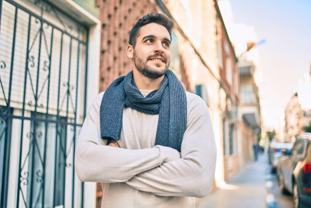 Fiatal spanyol férfi mosolyog boldogan visel sálat sétálva a városban. - Fotó, kép