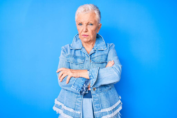Senior kaunis nainen siniset silmät ja harmaat hiukset yllään rento denim tyyli skeptinen ja hermostunut, paheksuva ilme kasvot ristissä kädet. negatiivinen henkilö.  - Valokuva, kuva