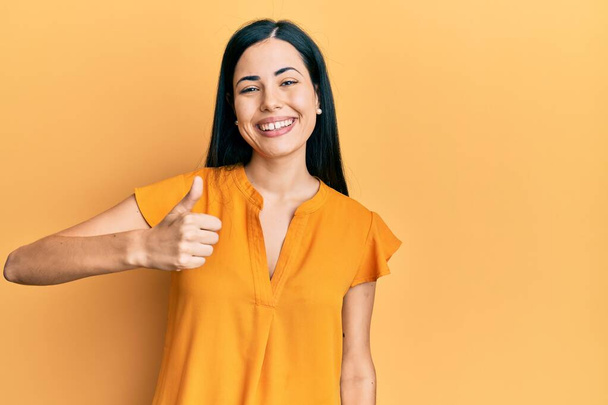 Beautiful young woman wearing casual clothes doing happy thumbs up gesture with hand. approving expression looking at the camera showing success.  - Φωτογραφία, εικόνα