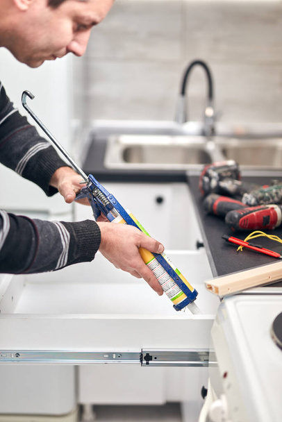 Handyman utilisant un joint adhésif silicone pour fixer les choses de maisons. - Photo, image