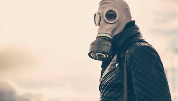 casual young man in a gas mask standing on the street in an empty city - Foto, afbeelding