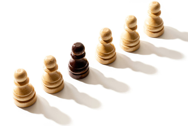 Row of white pawns with one black. Concept of racism and discrimination. - Photo, image