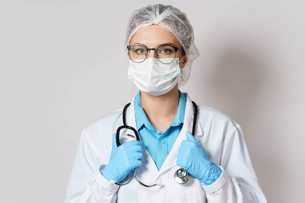 Young female doctor with a stethoscope on gray background - Foto, Imagem