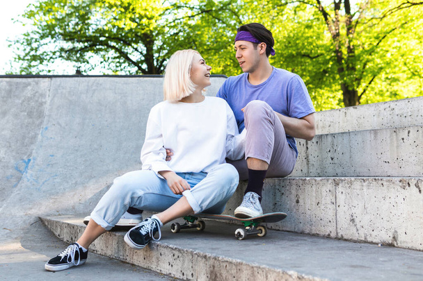 Portrait of happy and loving teenager couple in a skate-park - Fotoğraf, Görsel