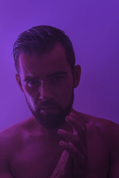 Portrait of handsome young man with wet skin in neon light - Foto, Imagem