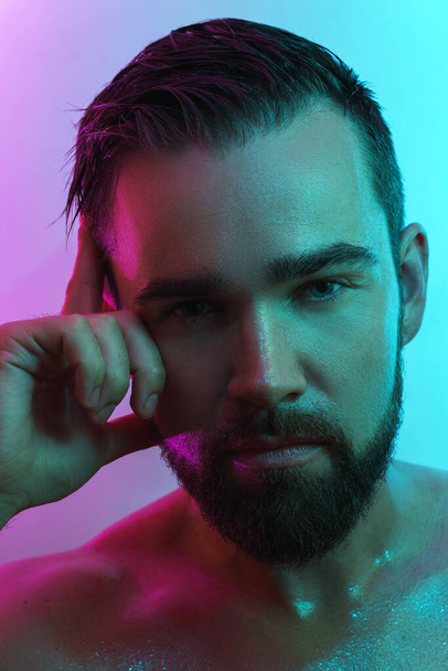 Portrait of handsome young man with wet skin in neon light - Foto, afbeelding