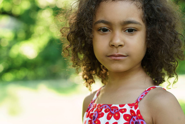 Closeup portrait of cute black girl in a city park - Zdjęcie, obraz
