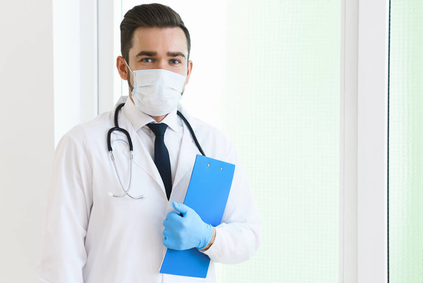 Young and confident doctor is holding the clipboard with a documents - Фото, зображення