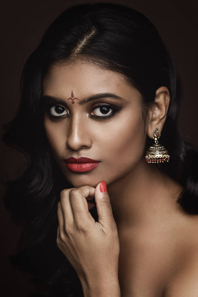 Portrait of Young Indian woman with beautiful makeup and hairstyle on brown background - Fotoğraf, Görsel