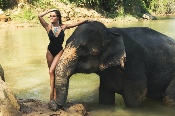 Happy young woman is bathing with the elephant in the river - Foto, Imagem