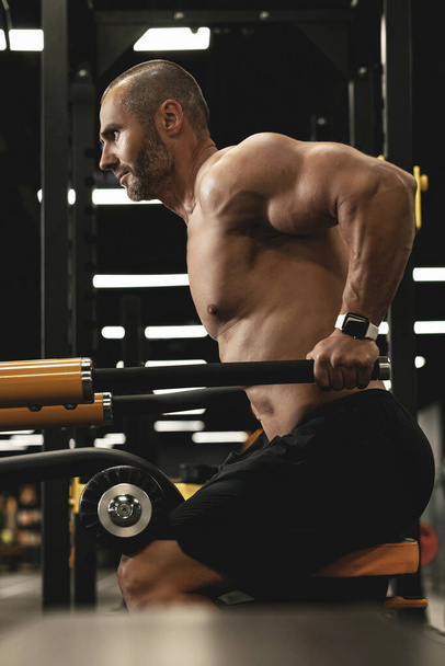 Muscular culturista haciendo inmersiones para tríceps y músculos del pecho durante su entrenamiento en el gimnasio - Foto, imagen