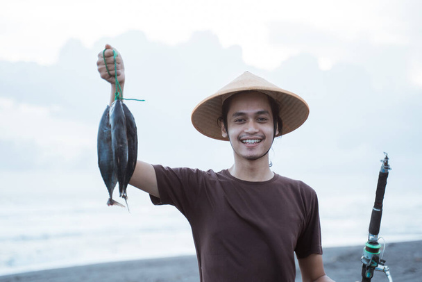 Happy young fisherman on the beach - Photo, image